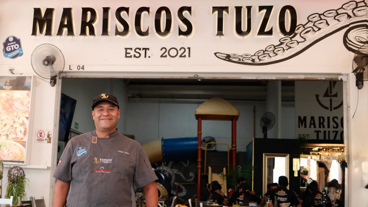 El TUZO en su local, frente al letrero de Mariscos TUZO