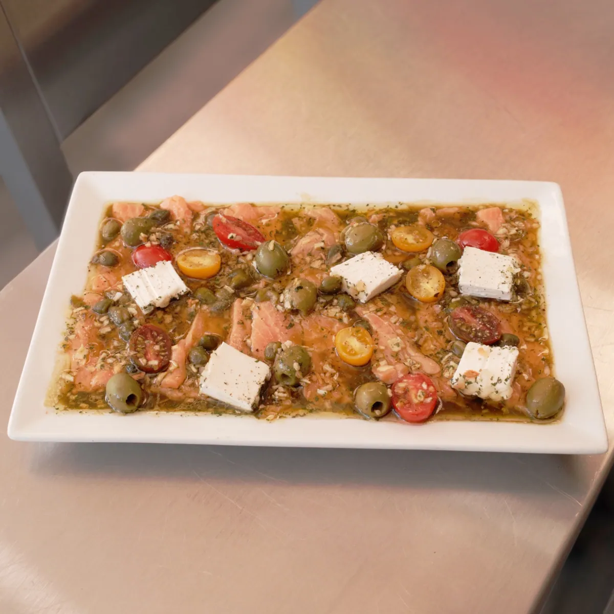 Carpaccio de salmón con jitomate cherry, aceitunas y alcaparras